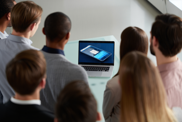 people crowding around a computer to watch a product demo video